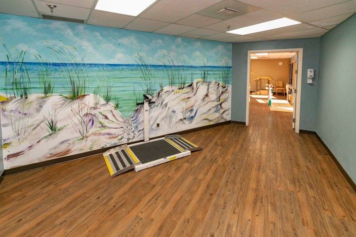 A gym interior with a mural painting and exercise equipment.