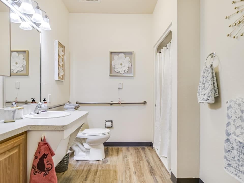 A clean and well-organized bathroom with a toilet, sink, and wall decor.