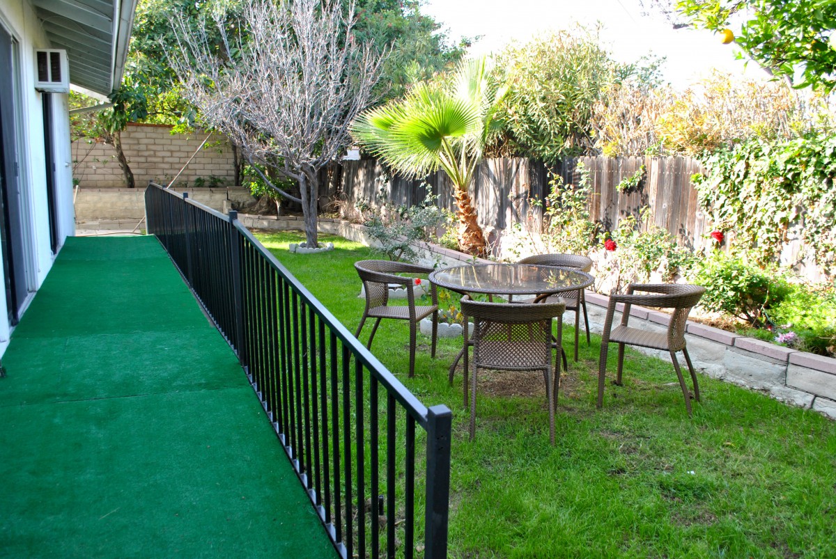 A tranquil backyard garden with a table, chairs, and lush greenery.