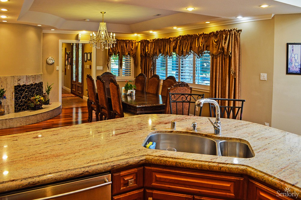 A luxurious kitchen and dining area featuring granite countertops, elegant wood cabinets, and a chandelier.