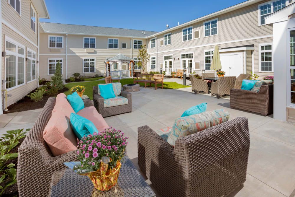 A cozy outdoor courtyard featuring wicker furniture with colorful cushions in a residential setting.