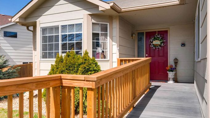 A house entrance with a wooden ramp and red front door.