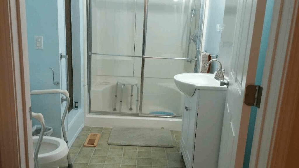 A modern bathroom featuring a shower with sliding doors, a sink with a mirror above it, and a tiled floor.