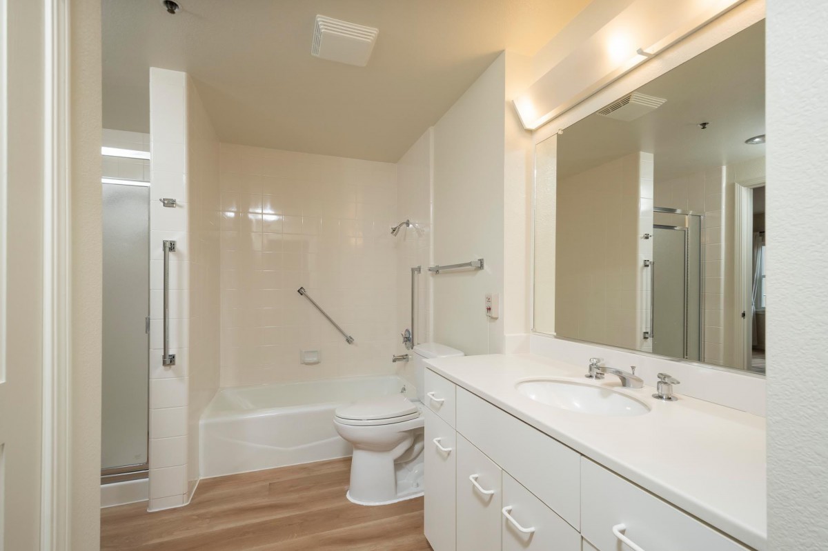 A modern bathroom with a bathtub, toilet, and white cabinetry.