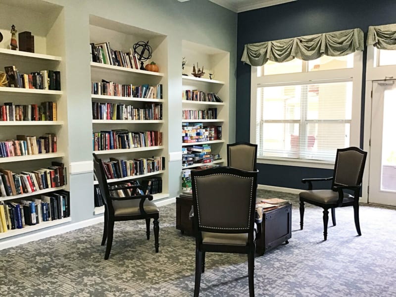 A cozy library space with bookshelves and chairs beside a large window.