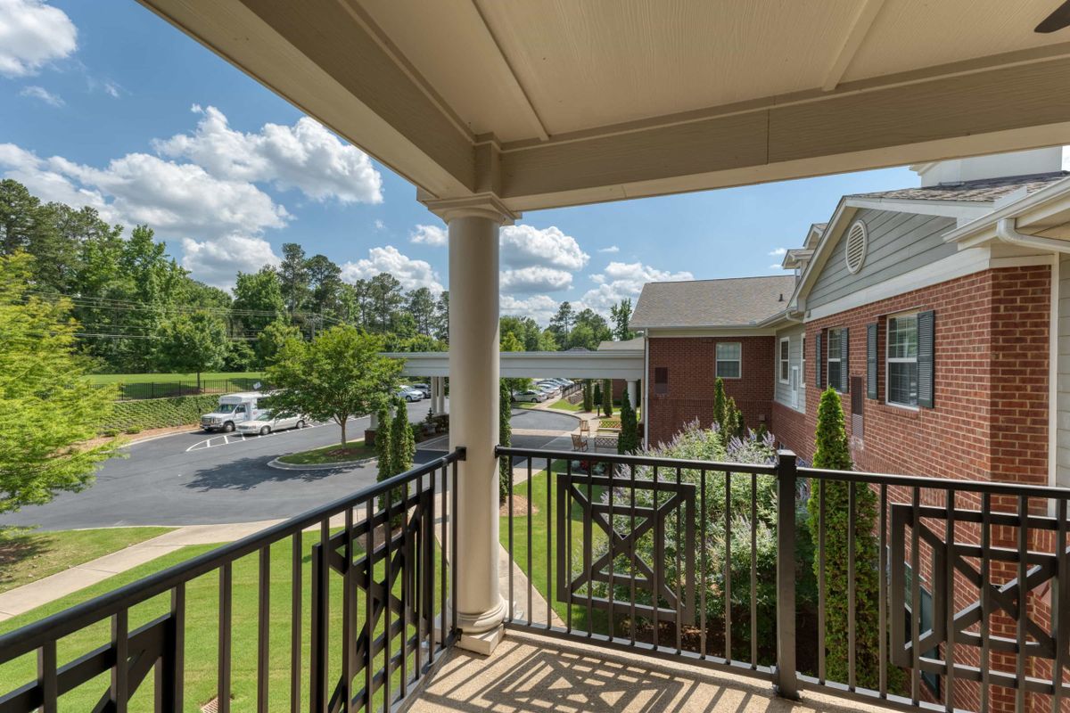A view from a balcony overlooking an apartment complex, with clear skies and lush greenery.