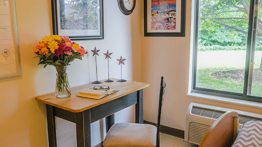 A cozy workspace featuring a small desk adorned with a vase of flowers and decorative art on the walls.