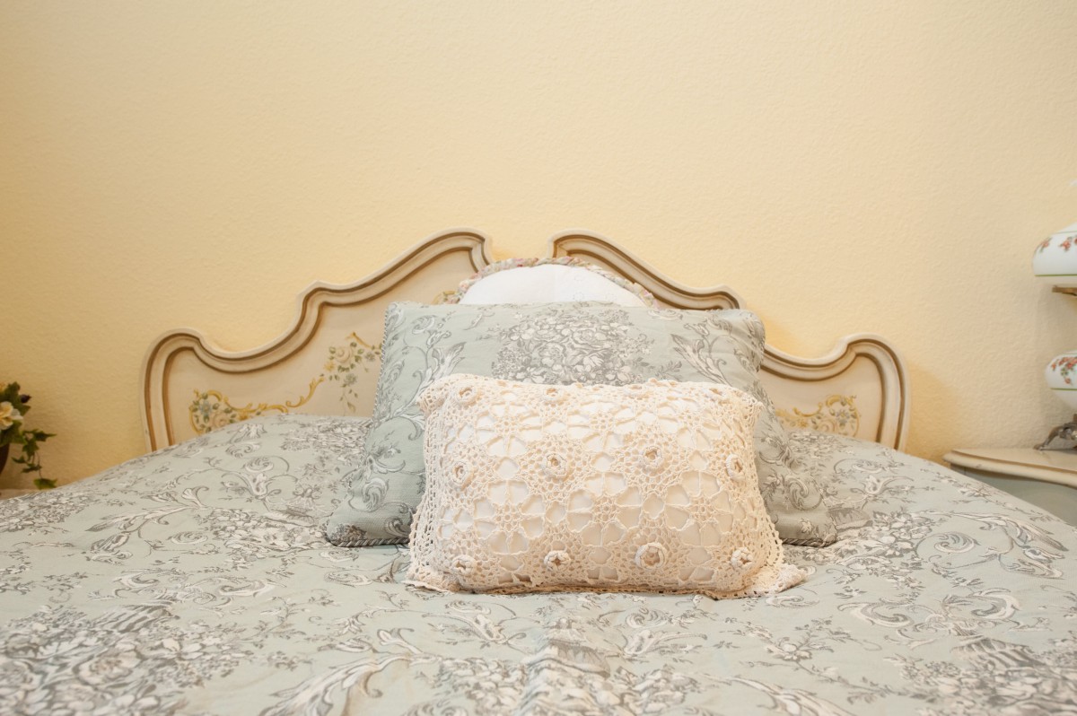 A neatly arranged bed with decorative pillows and an elegant headboard.