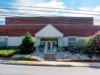Entrance of a brick commercial building with landscaped surroundings.