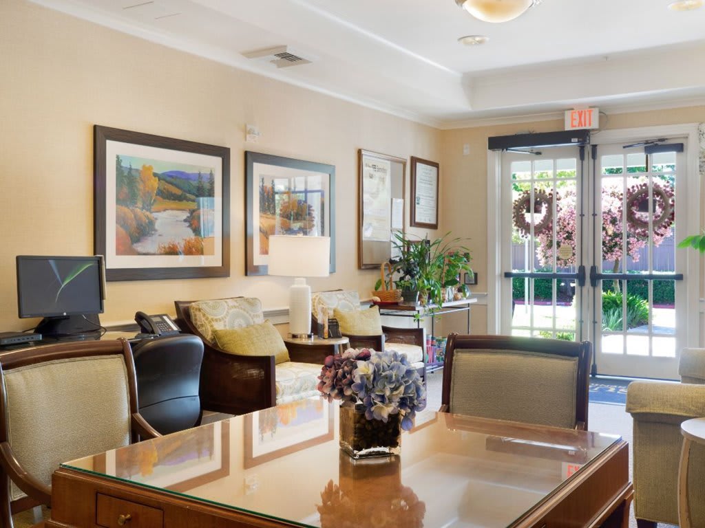 A cozy lobby with comfortable seating, artwork on the walls, and decorative plants by the entrance.