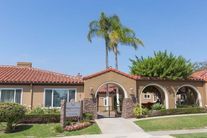 A sunny day with a building featuring an archway and surrounded by palm trees.