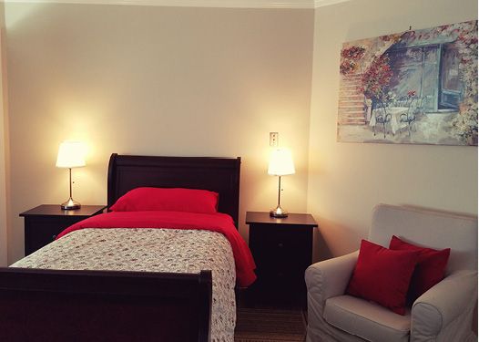 A cozy bedroom with a neatly made bed, nightstands, and warm lighting.