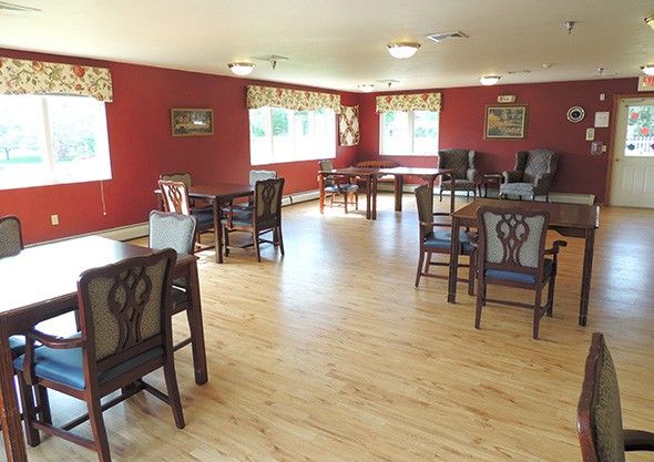 A spacious dining room with elegant chairs and tables, featuring hardwood floors and large windows.