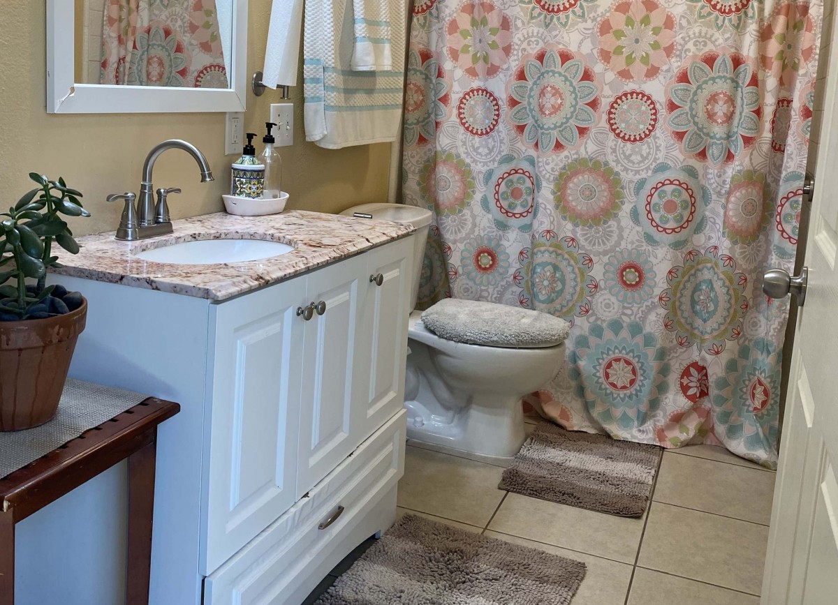 A cozy bathroom with a patterned shower curtain and white vanity.
