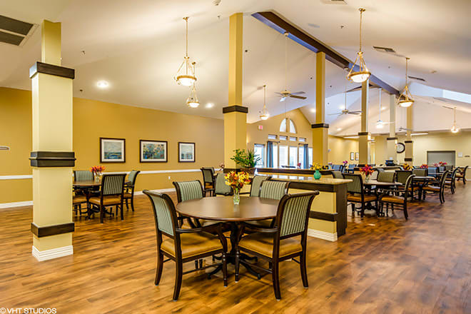 A cozy dining area with tables, chairs, and warm lighting.