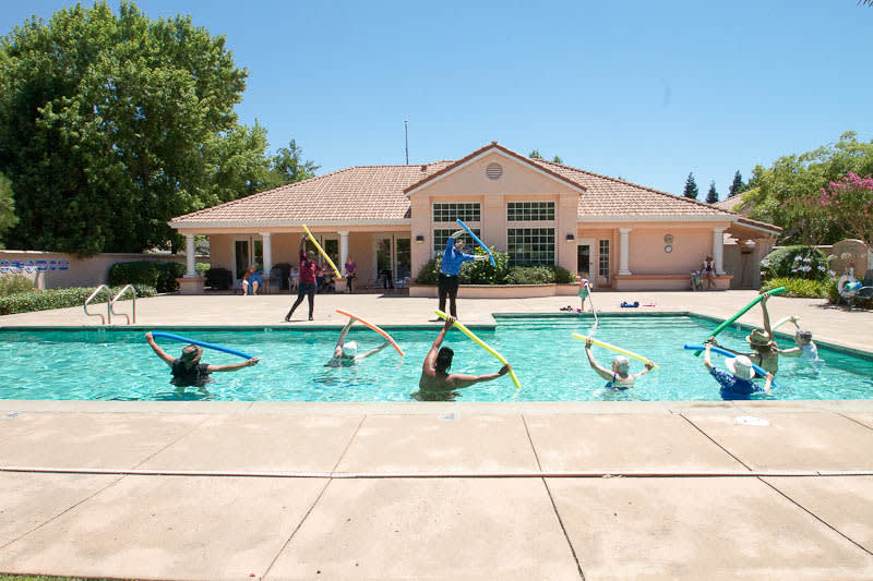 A group of people participating in a water aerobics class in an outdoor pool.