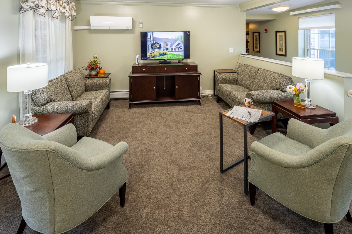 A cozy living room with multiple sofas, a television, and a coffee table on a carpeted floor.