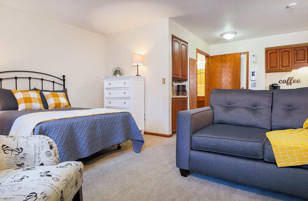 A cozy bedroom with a bed, dresser, and comfortable chair.