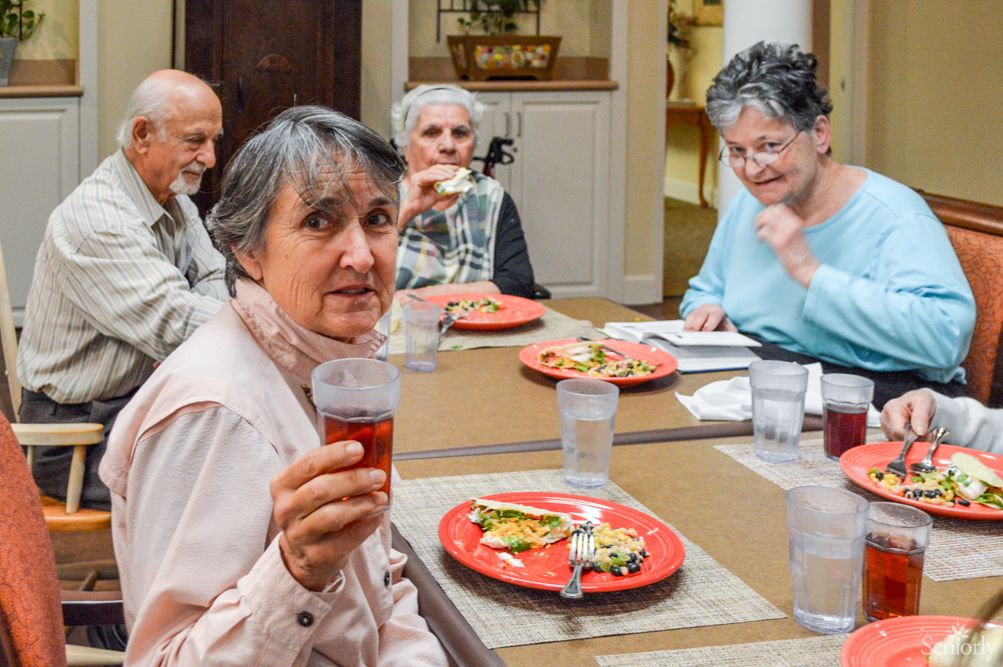 A group of seniors enjoying a meal together at a dining table.