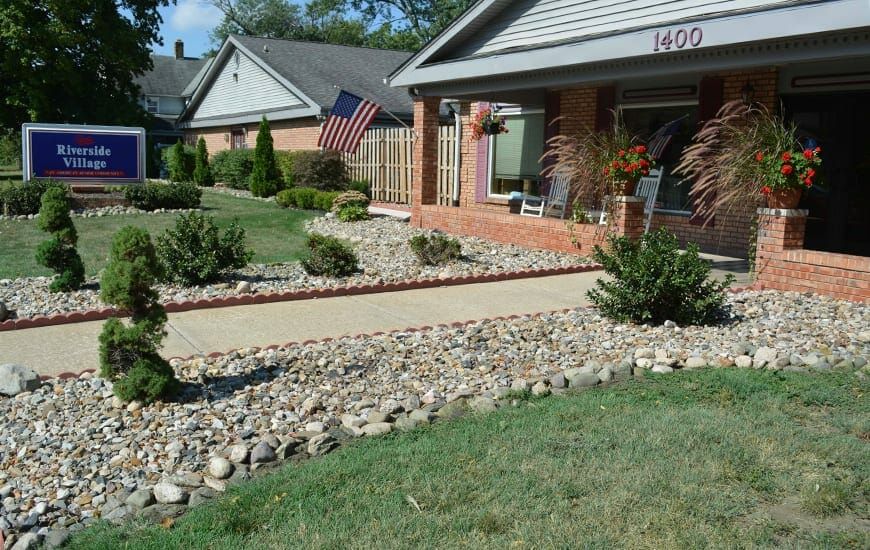 A suburban house with a landscaped front yard featuring a stone pathway and an American flag.
