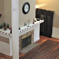A cozy living room with a decorated fireplace and a wall clock.