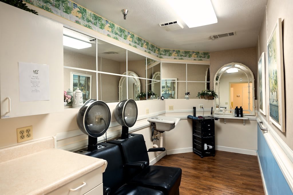 An interior view of a salon featuring hair drying chairs and mirrors.
