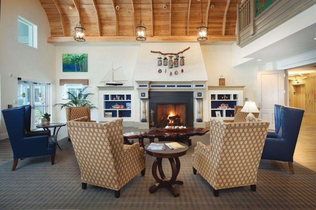 A cozy living room with a fireplace, comfortable seating, and a wooden ceiling.