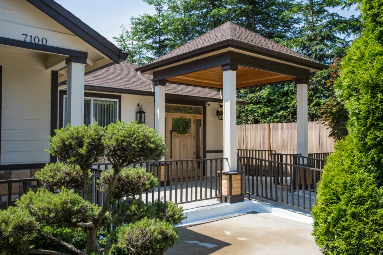 A modern house with a covered porch and well-maintained garden.