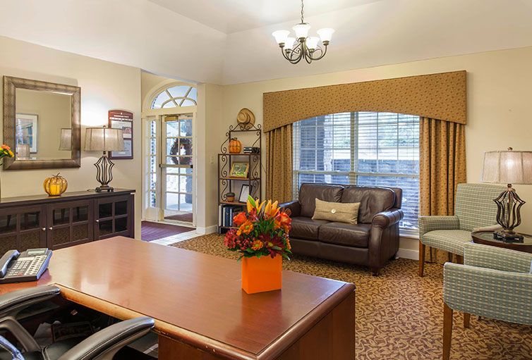 A cozy office interior with a desk, sofa, and decorative elements.
