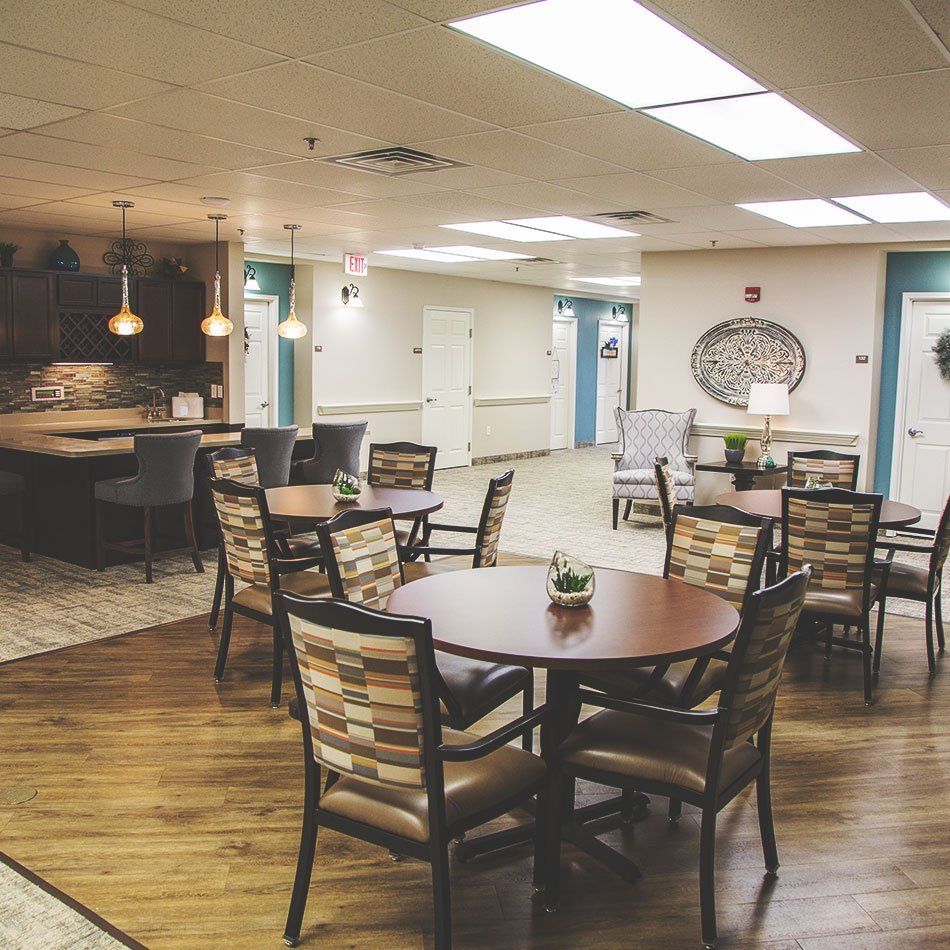 A well-lit dining area with wooden tables and upholstered chairs.