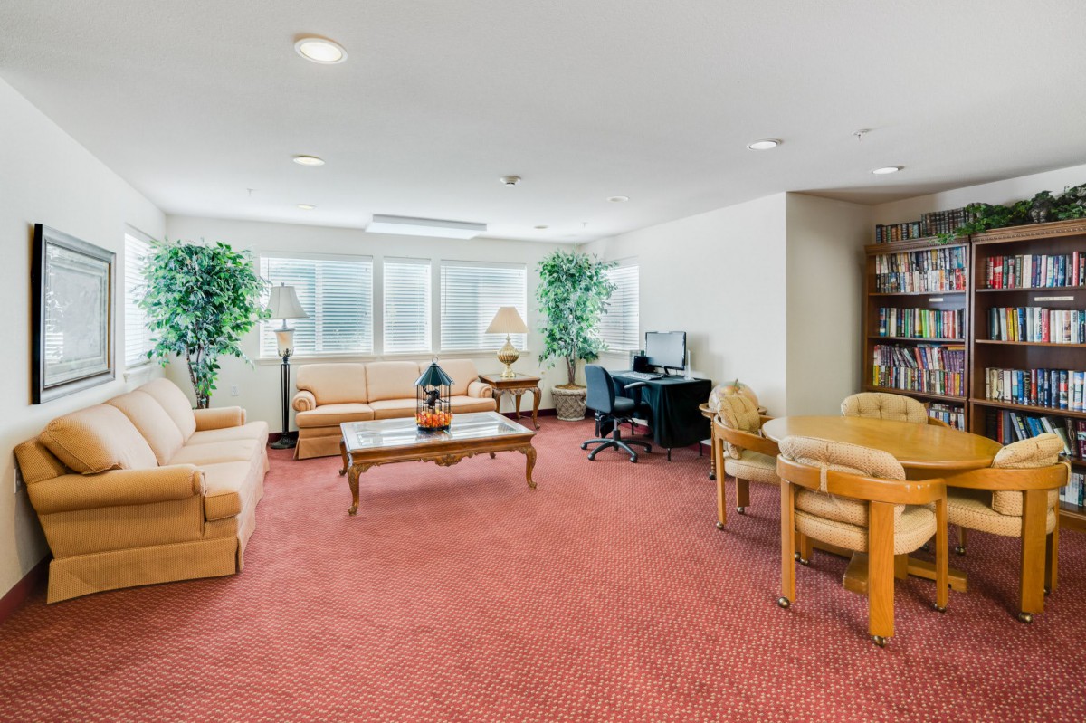 A cozy lobby area with sofas, a coffee table, chairs, and decorative plants.