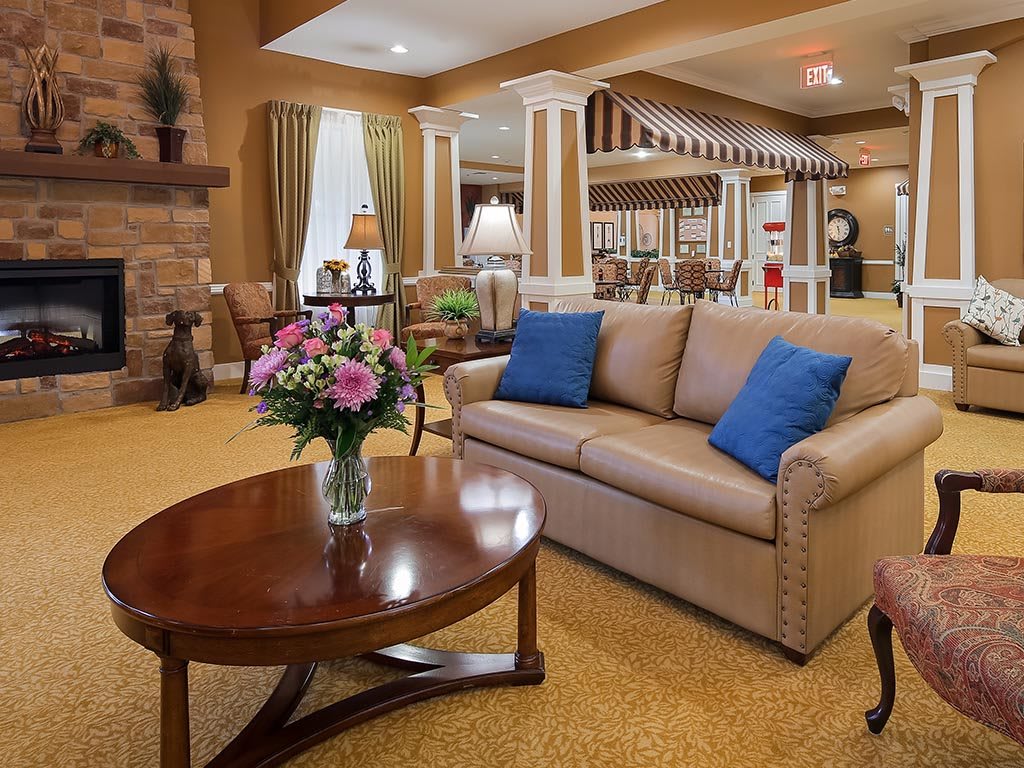 A cozy and well-decorated living room featuring a comfortable sofa with blue pillows, a wooden coffee table with a vase of flowers, and warm lighting.