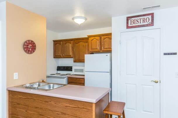 A cozy kitchen interior with wooden cabinets, a fridge, oven, and a sink.
