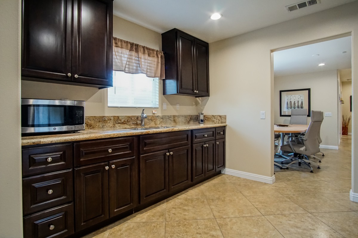 A spacious kitchen with dark wooden cabinets and a tiled floor.