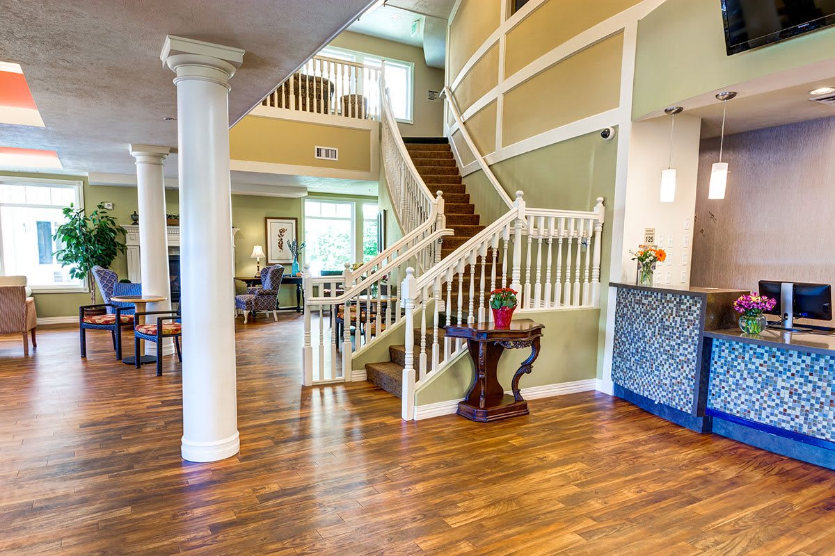 Spacious lobby with a grand staircase and wooden flooring.