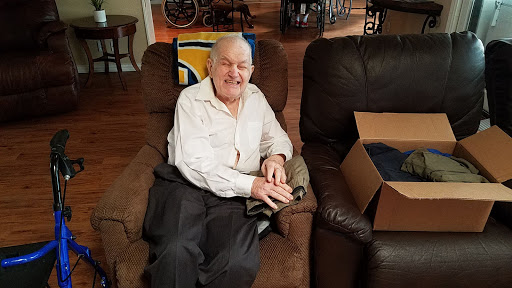 An elderly man sitting comfortably in a recliner with a smile.