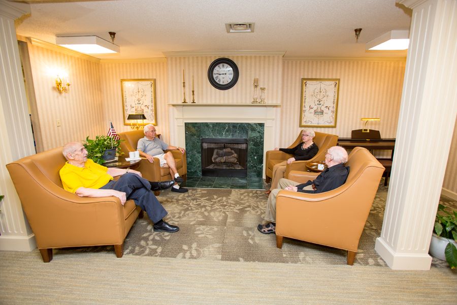 A group of seniors relaxing in a cozy seating area with a fireplace.