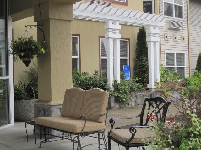 A cozy outdoor patio area with cushioned seating and a pergola overhead.