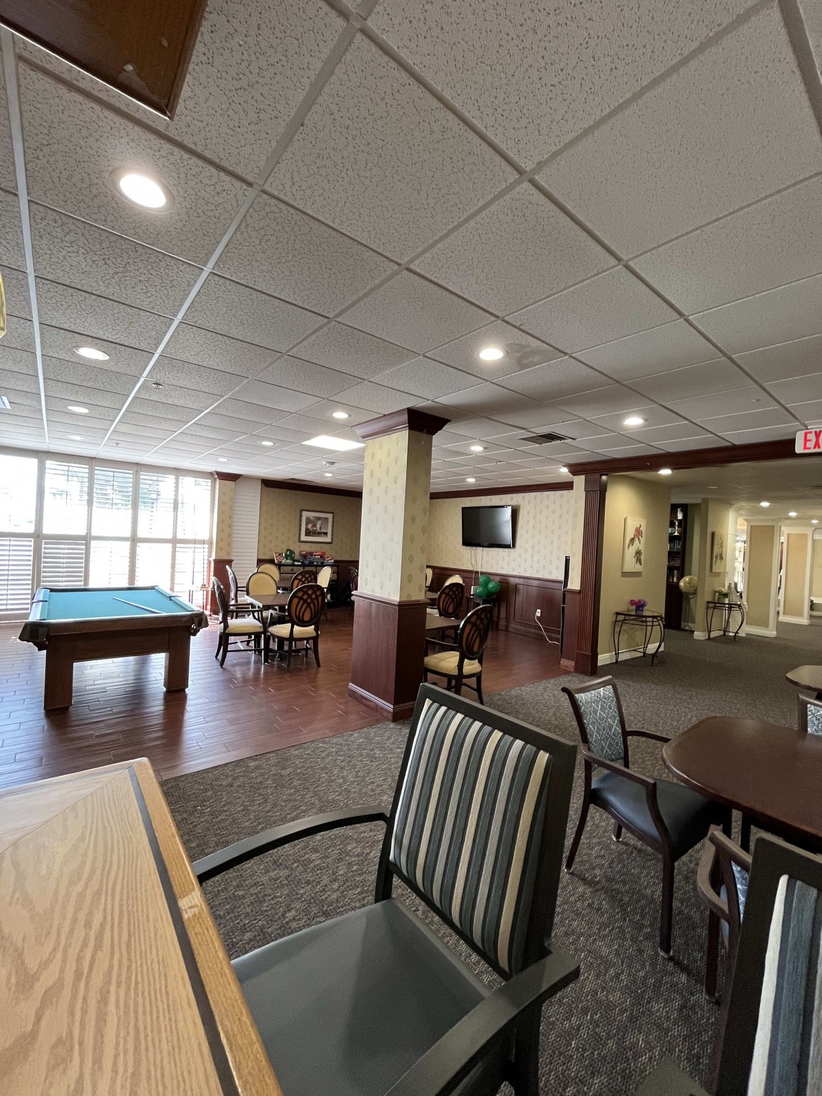 A spacious recreation room featuring a pool table, seating areas, and a television for community enjoyment.