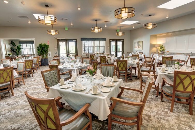 An elegant dining room with neatly arranged tables and chairs, set for guests.