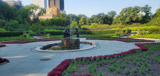 A serene park scene featuring a fountain and colorful flower beds.