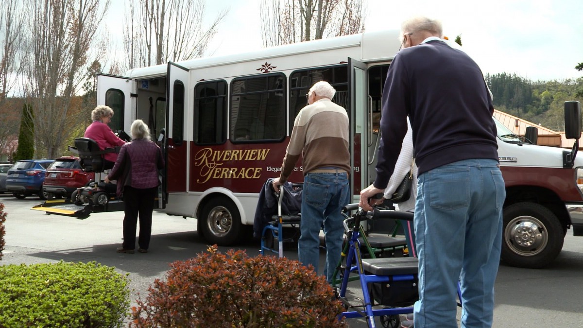 A group of elderly individuals with walkers boarding a bus.