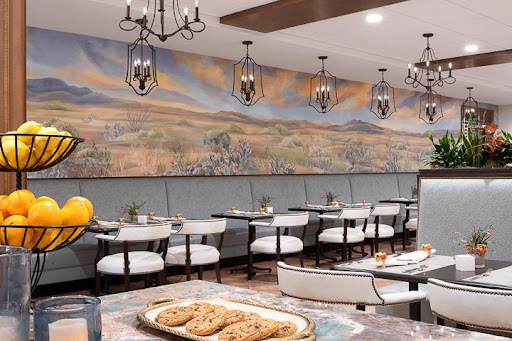 A beautifully designed dining area featuring elegant lighting, a stunning mural, and a tempting display of cookies.