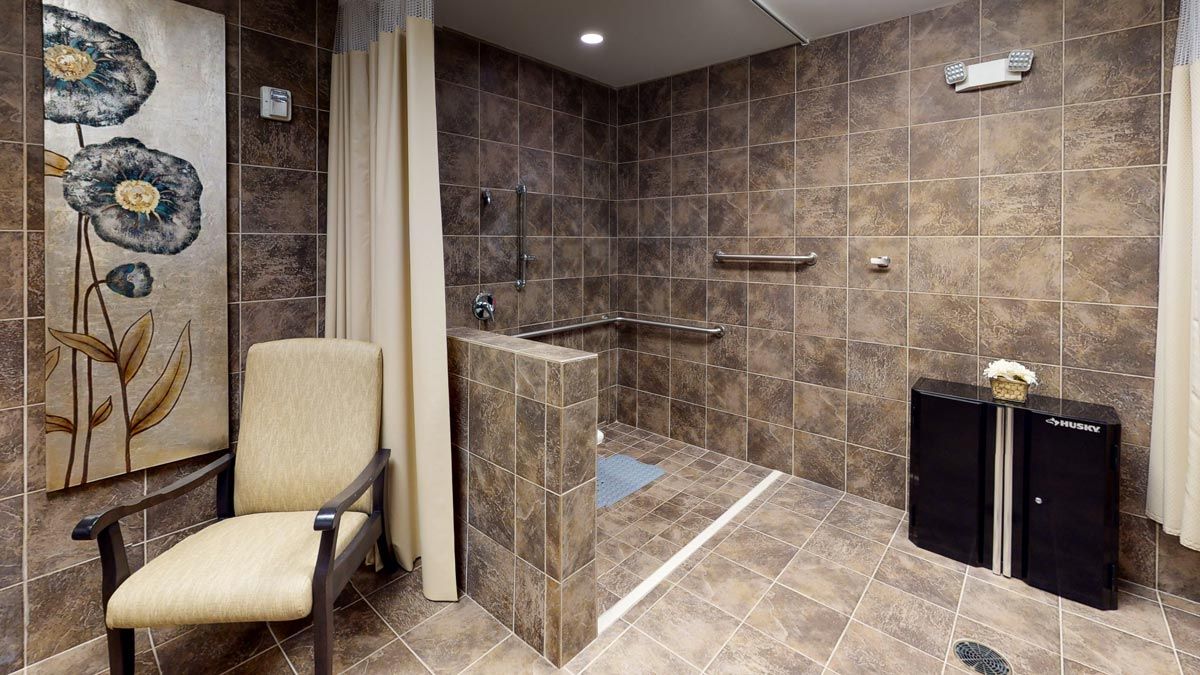 An accessible bathroom with a walk-in shower, grab bars, and seating area.