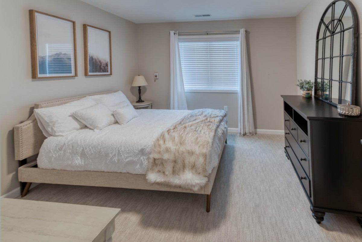 A modern and minimalist bedroom featuring a neatly made bed, light color scheme, and simple decor.