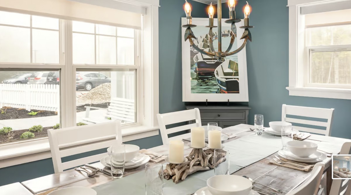 A modern dining room with elegant table settings, a decorative chandelier, and artwork on the wall.