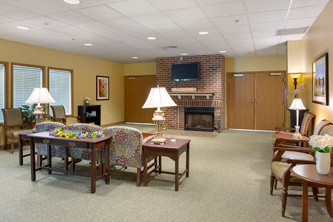 A cozy lounge area featuring a brick fireplace, comfortable seating, and a television.