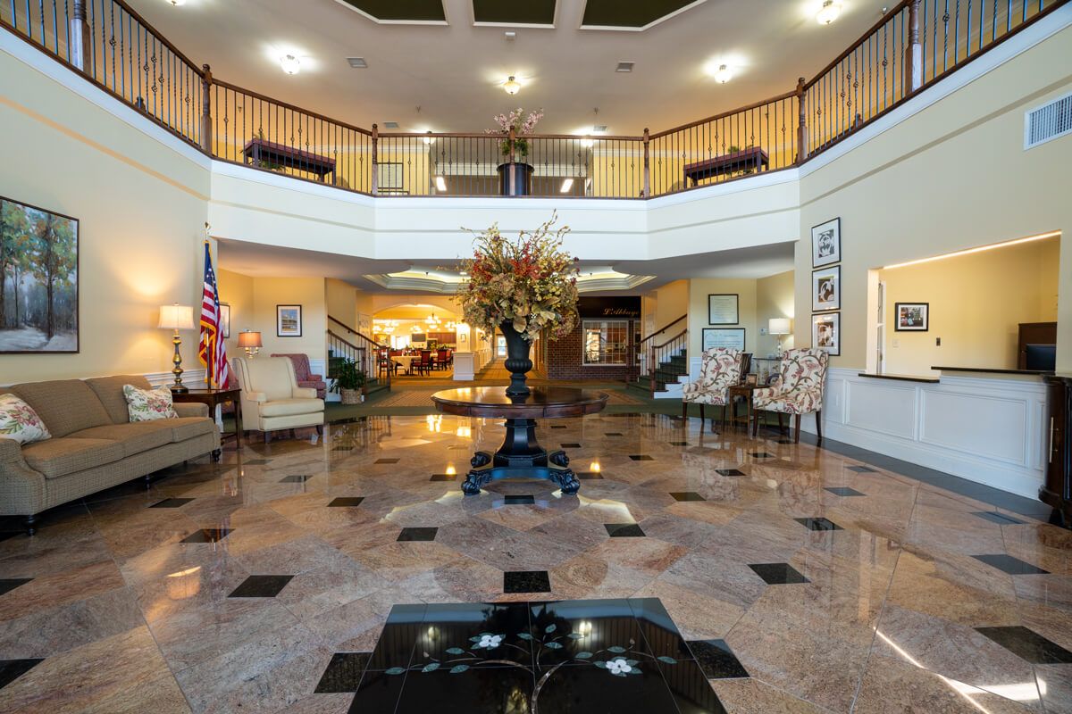 A spacious and elegant hotel lobby with a central floral arrangement and grand staircase.