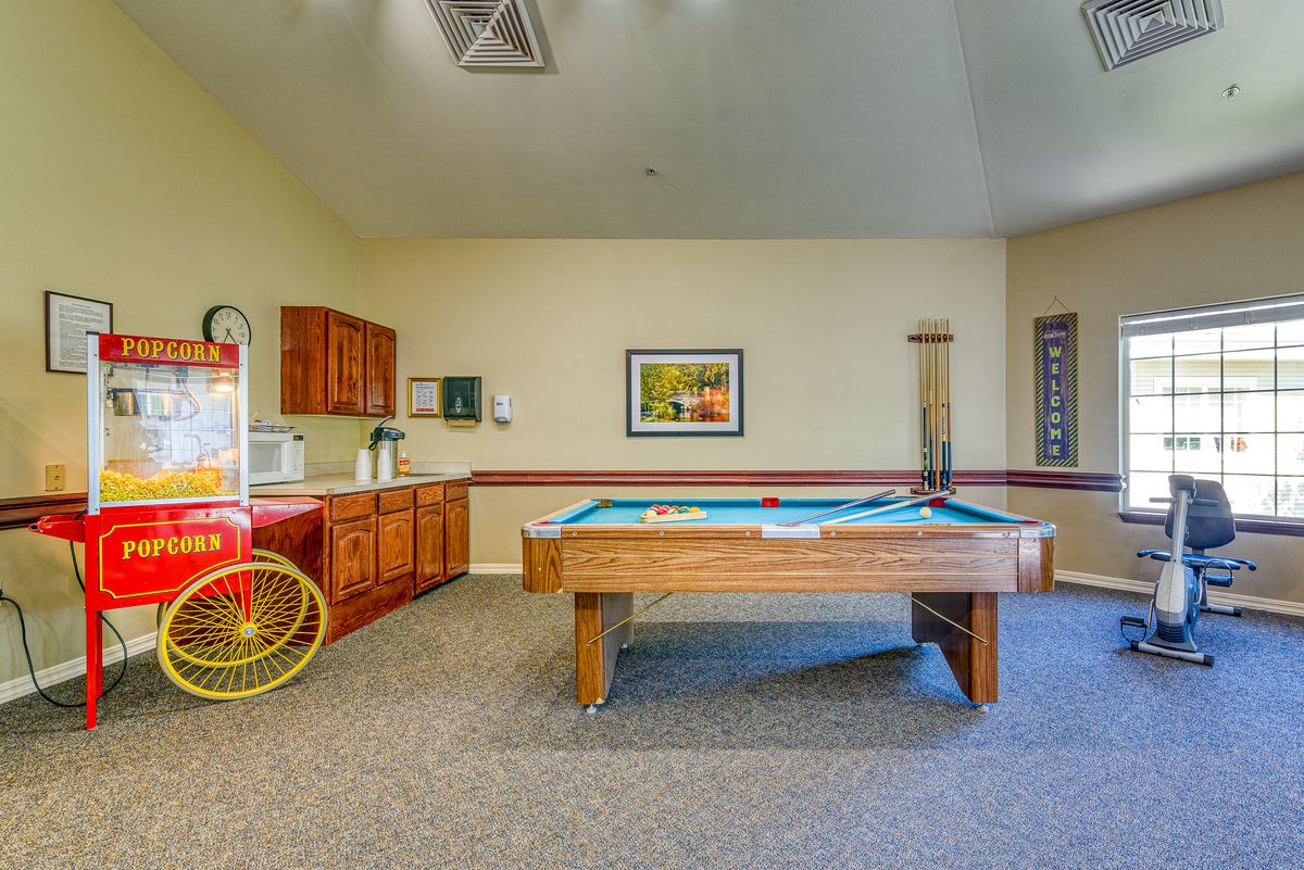 A cozy game room featuring a pool table and a popcorn machine for entertainment.