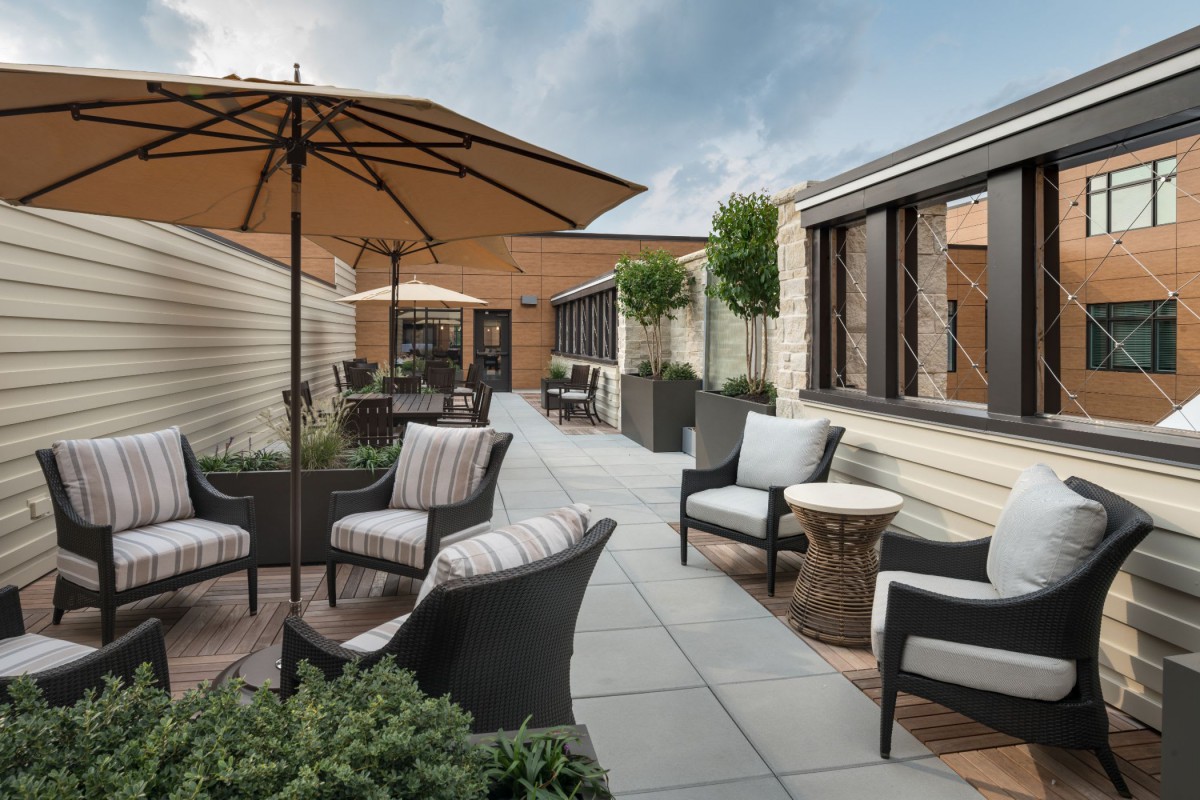 A cozy outdoor patio with comfortable seating and umbrellas on a rooftop terrace.